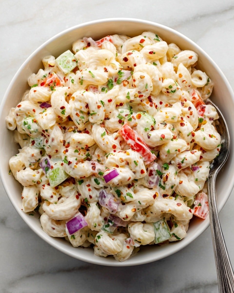 A close-up of a white bowl filled with creamy macaroni salad, showing three layers: a base layer of elbow macaroni coated in white mayonnaise sauce, scattered with small green pepper pieces, diced red bell peppers, and purple onion chunks evenly mixed throughout. The bowl rests on a white marbled surface with a soft background that includes blurred greenery. The macaroni looks soft and shiny, with bits of finely chopped herbs sprinkled on top adding a touch of green. Photo taken with an iphone --ar 4:5 --v 7 — Gordon Ramsay Macaroni Salad, Classic pasta salad, creamy mac salad, tangy mustard pasta, easy summer side dish